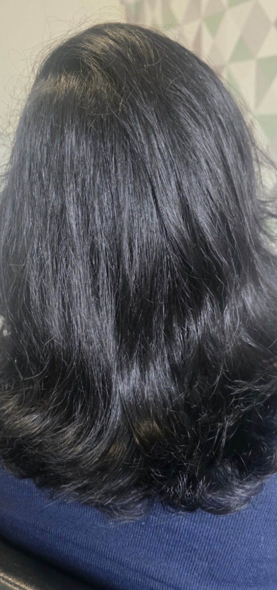 Donker haar in laagjes, achteraanzicht, voor de geometrische salonwand